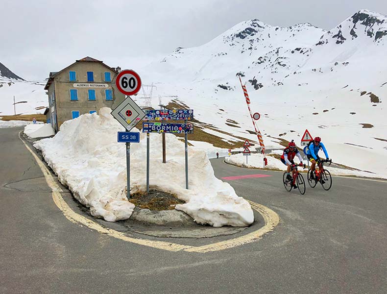 Two cyclists riding up the snow covered passo Stelvio